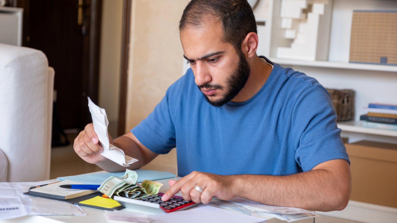 Young bearded man calculating living costs in living room