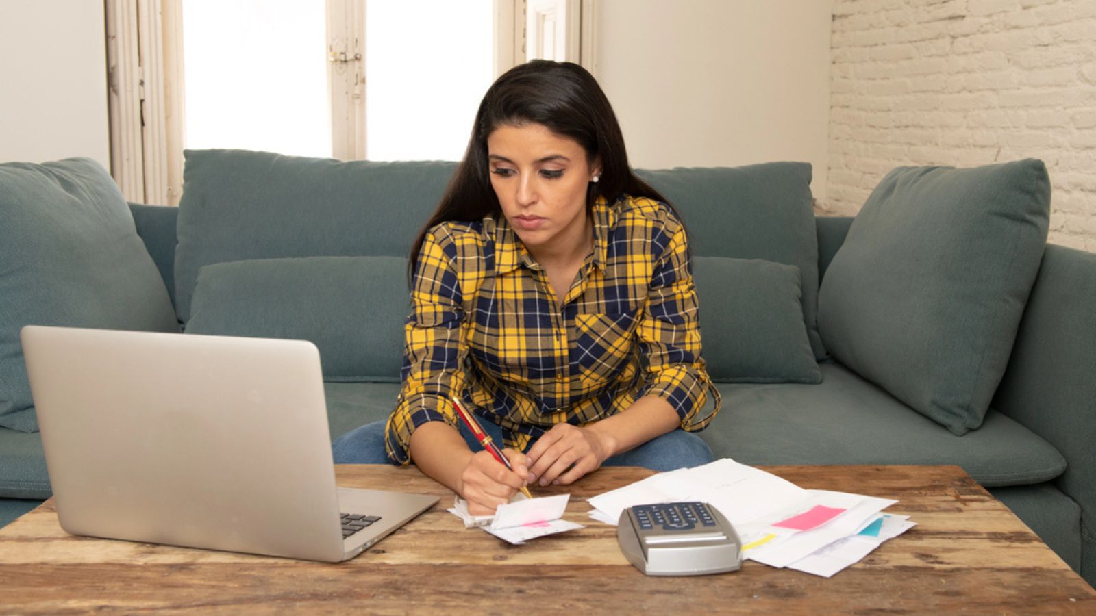 Young worried woman in stress banking and accounting debt bills, bank papers, expenses and payments feeling desperate in a bad financial situation. Money Concept
