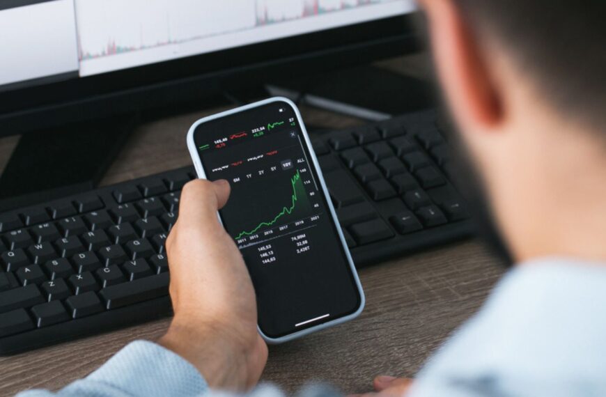 Stock market phone in the hand and desktop computer green and red charts