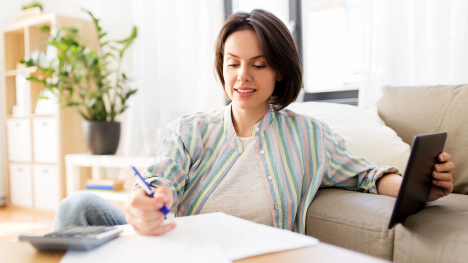 Woman with tablet pc, bills and calculator at home. Money Concept.