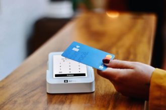 a person holding a credit card in front of a machine; credit cards