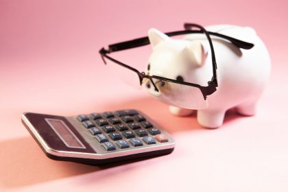 A piggy bank wearing glasses next to a calculator.; debt consolidation