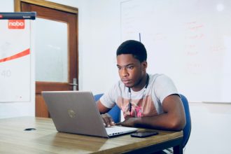 man in grey shirt using grey laptop computer; student loans