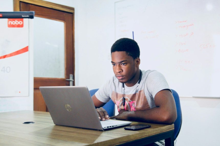 man in grey shirt using grey laptop computer; student loans