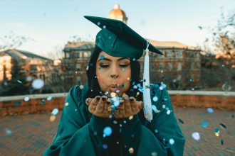 woman wearing academic dress; paying off student loans