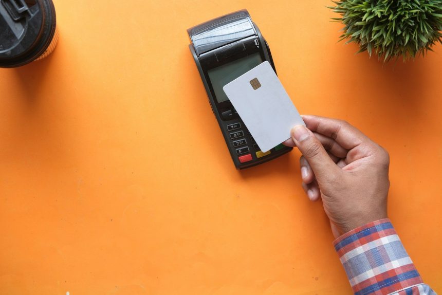 person holding black and white electronic device; minimum payments on your credit card