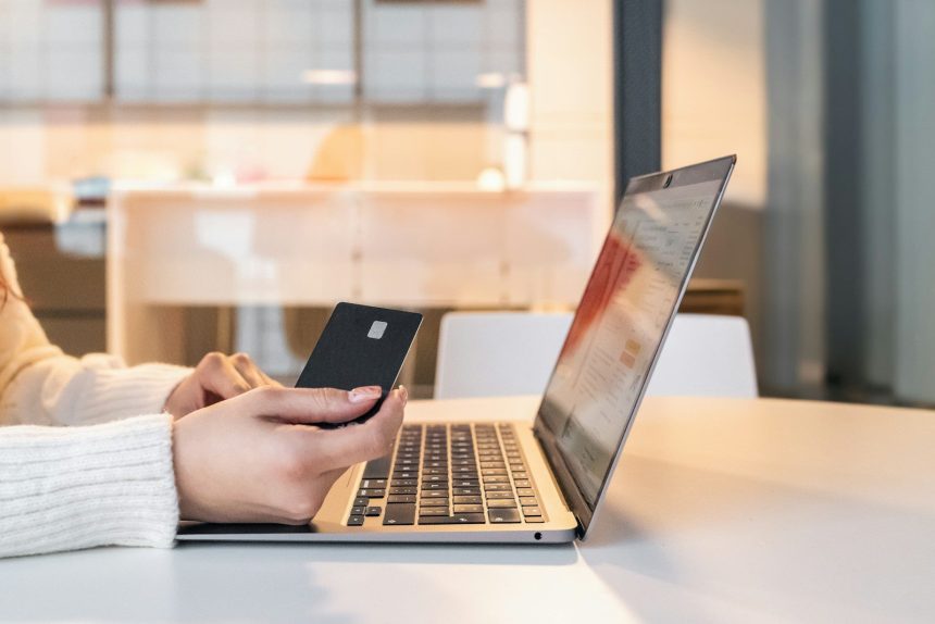 a woman sitting in front of a laptop computer holding a cell phone; income-driven repayment