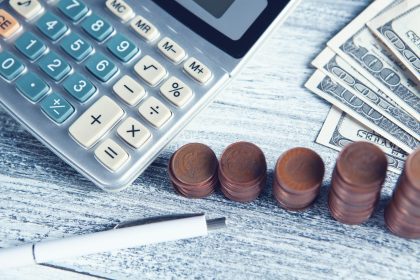 a calculator, pen, and money on a table; debt settlement