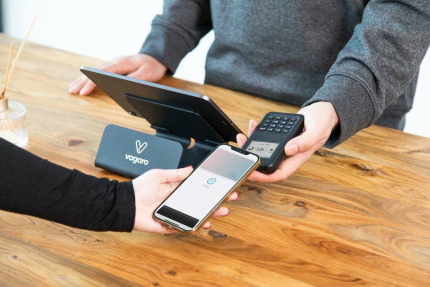 a person holding a cell phone and a laptop on a table; balance transfers