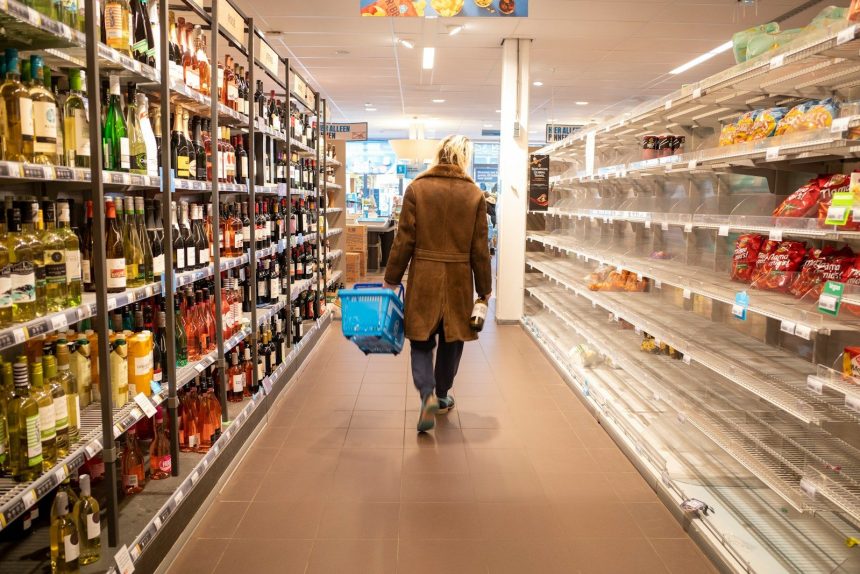 woman in brown coat walking on hallway; how to save money on groceries