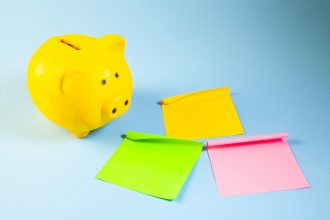 A yellow piggy bank with three colorful sticky notes.; how to stick to a budget