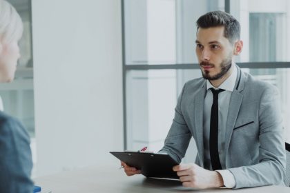 Two people in a business meeting with a clipboard.; how to ask for a raise