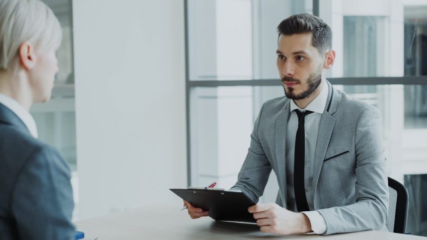 Two people in a business meeting with a clipboard.; how to ask for a raise
