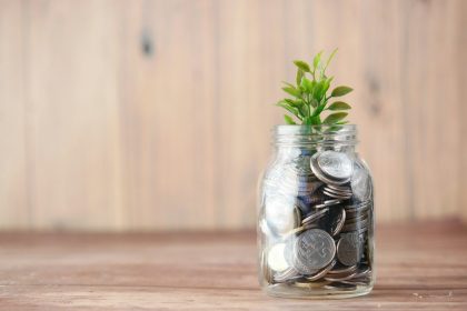 a glass jar filled with coins and a plant; passive income ideas