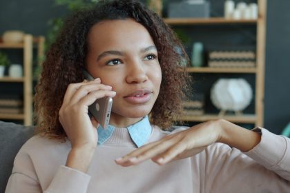 Young woman talking on a smartphone at home; how to handle debt collectors