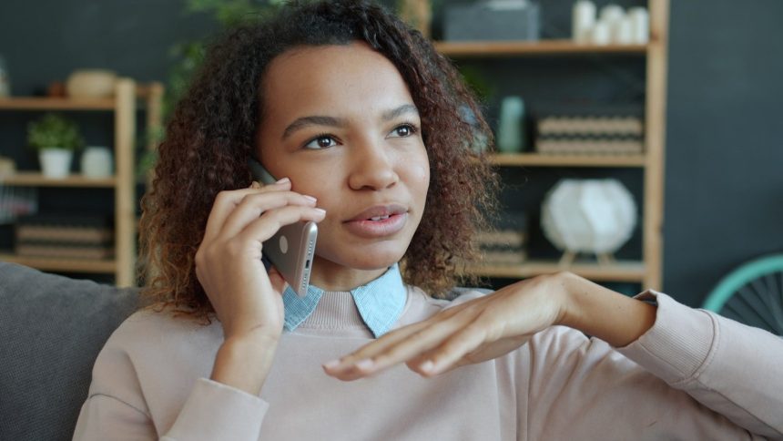 Young woman talking on a smartphone at home; how to handle debt collectors