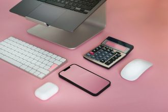 a calculator, keyboard, mouse and cell phone on a pink surface; budgeting for freelancers
