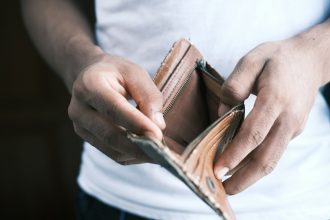 person holding brown leather bifold wallet; national debt