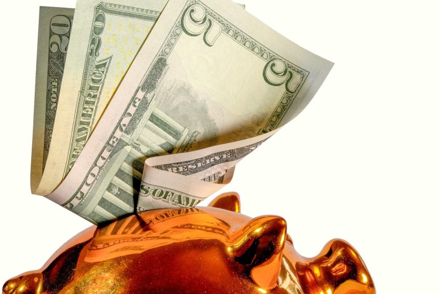 Us dollar bills being inserted into a piggy bank; what is a high-yield savings account