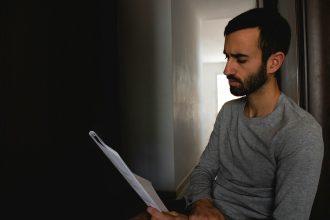 man in gray crew neck shirt holding white printer paper; improve credit score in 6 months