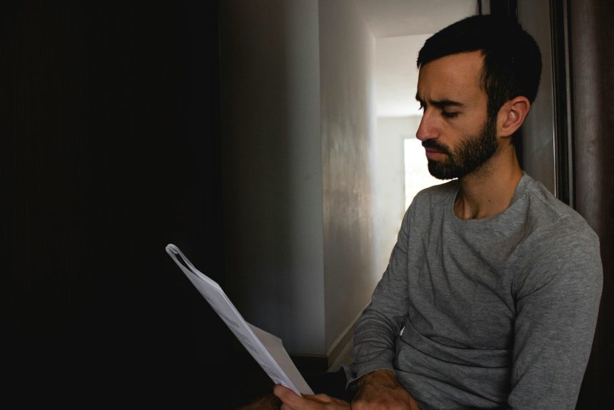 man in gray crew neck shirt holding white printer paper; improve credit score in 6 months