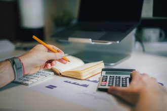 a person sitting at a desk with a calculator and a notebook; what is debt-to-income ratio