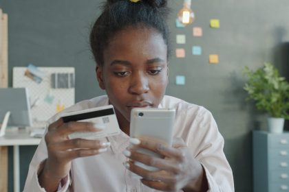 Woman holding credit card and smartphone for online shopping.; credit card debt