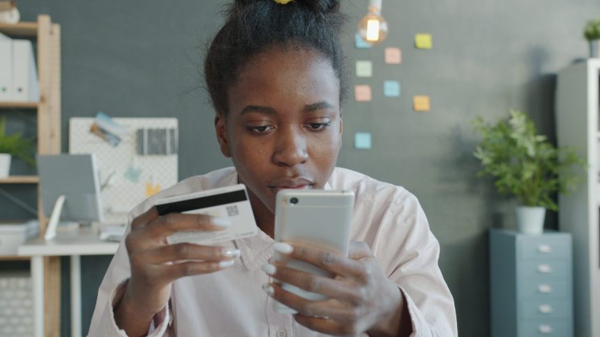Woman holding credit card and smartphone for online shopping.; credit card debt