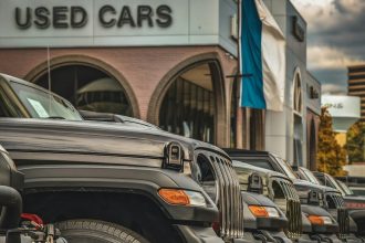 a row of parked cars in front of a used car store; auto loan debt