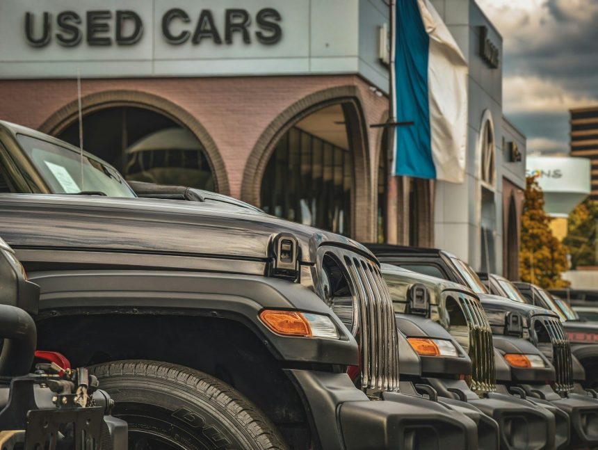a row of parked cars in front of a used car store; auto loan debt