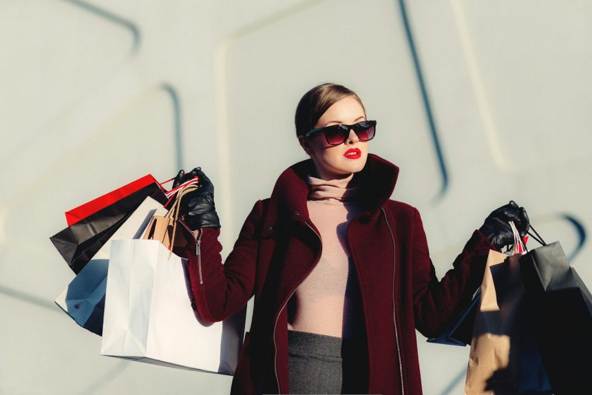 photo of woman holding white and black paper bags; doom spending