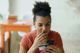 Woman looking at phone with credit card in hand; college students