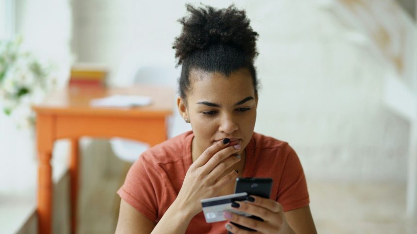 Woman looking at phone with credit card in hand; college students