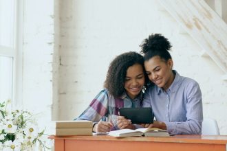 Two women reading a book together; wedding debt