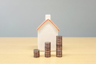a house and stacks of coins on a table; household debt