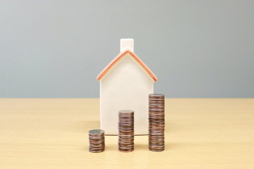 a house and stacks of coins on a table; household debt