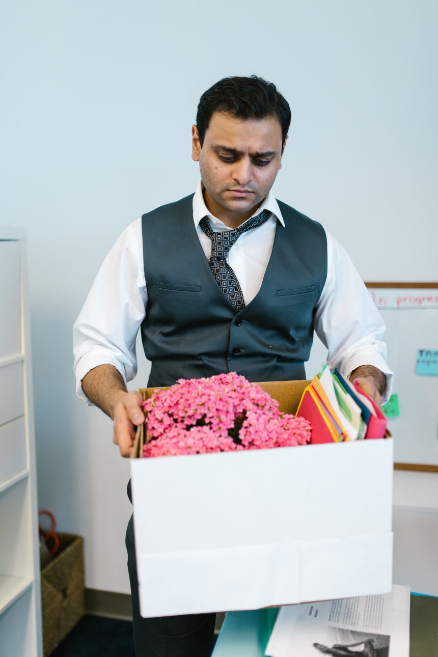 Man packing a box after a layoff, reflecting how layoffs and debt are rising together in 2026