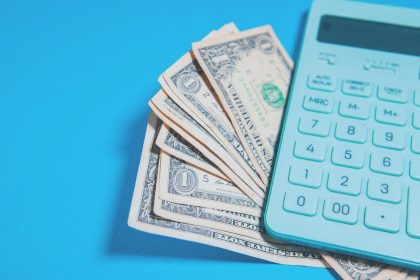 Us dollar bills and a calculator on blue background; ACA premium increases